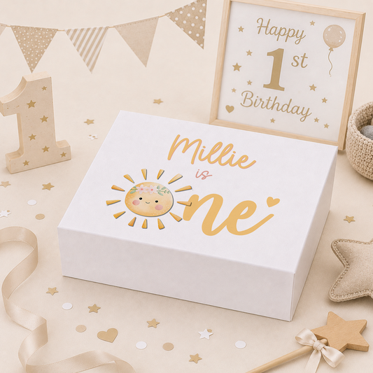 Personalised sunshine 1st birthday keepsake box in gold, with a smiling sun wearing a blossom crown and 'Millie is one' style lettering for the child's name