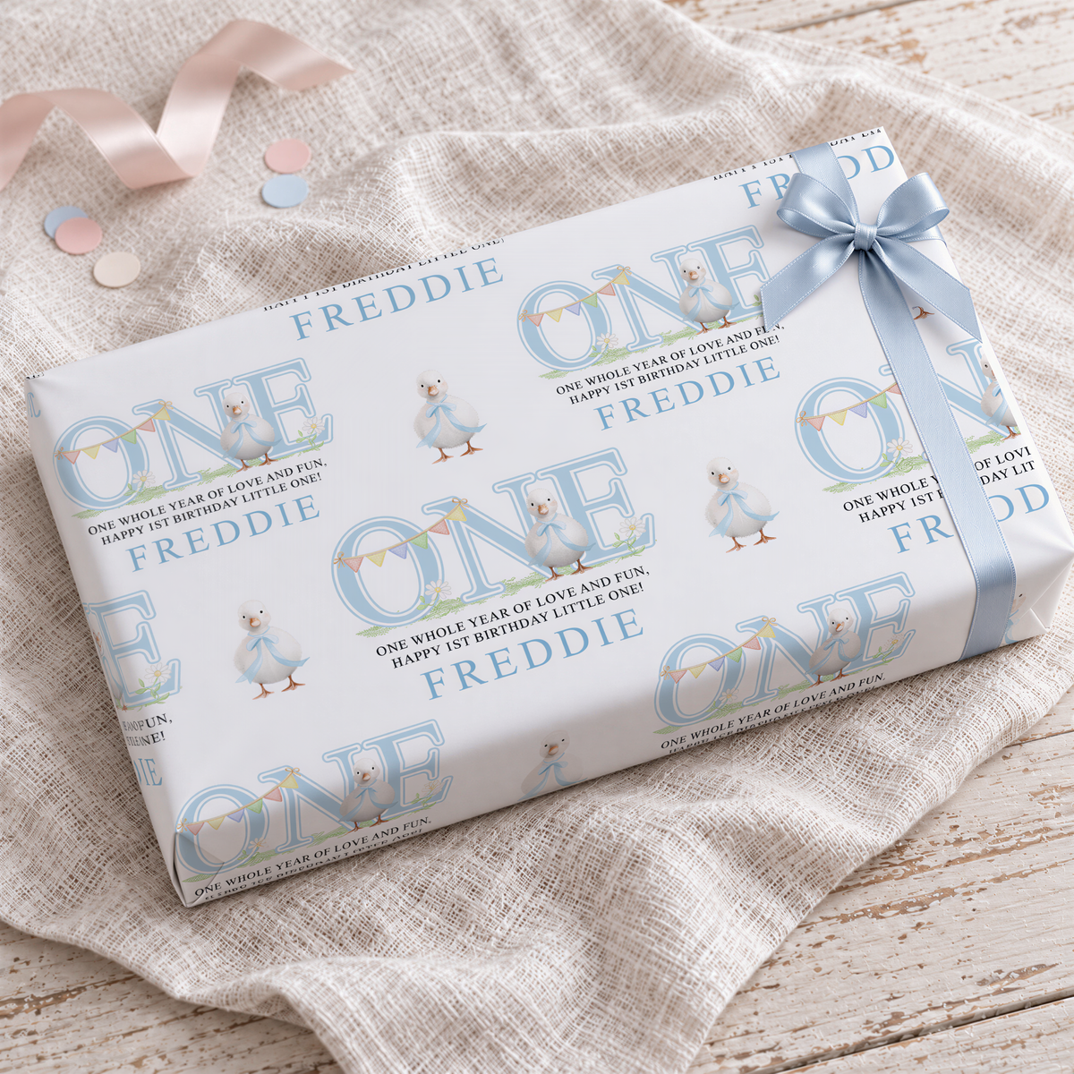 a gift box with a blue ribbon and a repeating pattern of the word "FREDDIE" on it.