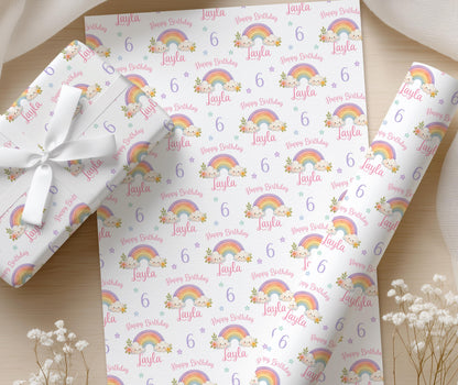 Roll of personalised rainbow birthday wrapping paper displaying the repeating colourful rainbow pattern.