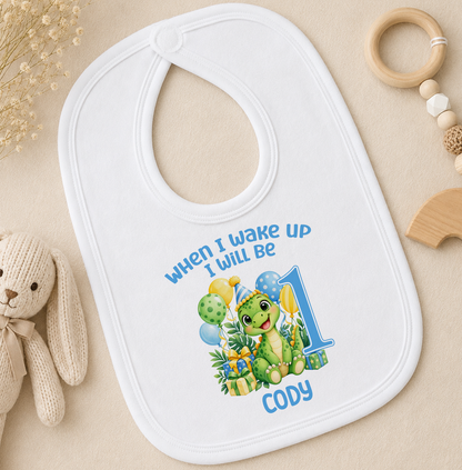 Matching personalised white baby bib with the When I Wake Up I Will Be 1 green dinosaur and balloons design and the name Cody