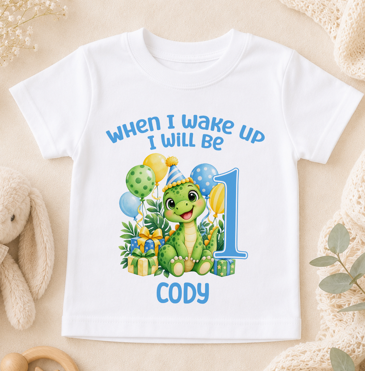 Personalised white baby t-shirt printed When I Wake Up I Will Be 1 with a green dinosaur, balloons and the name Cody
