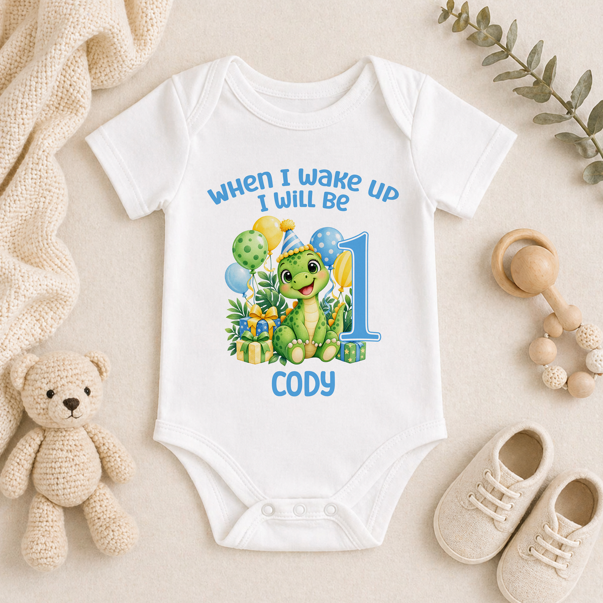 Personalised white baby vest printed When I Wake Up I Will Be 1 with a green dinosaur, balloons and the name Cody