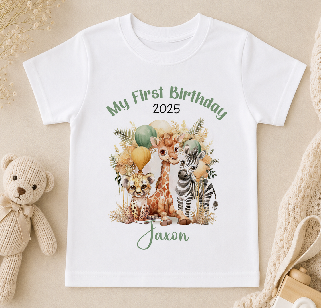 A white t-shirt with a printed design of a giraffe, zebra, and other animals, along with the text "My First Birthday 2025" and "Jaxon".