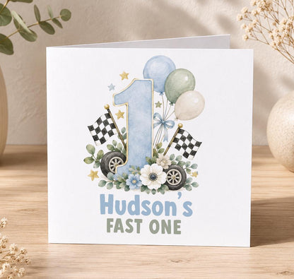 Personalised Fast One 1st birthday card – blue number 1 with chequered flags, wheels and balloons, Hudson’s Fast One