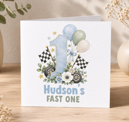 Personalised Fast One 1st birthday card – blue number 1 with chequered flags, wheels and balloons, Hudson’s Fast One