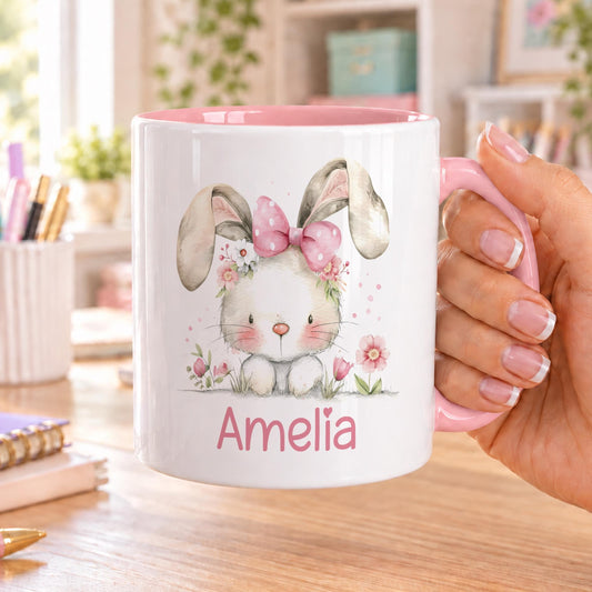 Personalised bunny mug with pink handle and inside, printed with a watercolour rabbit wearing a pink bow among pink flowers and a name in pink