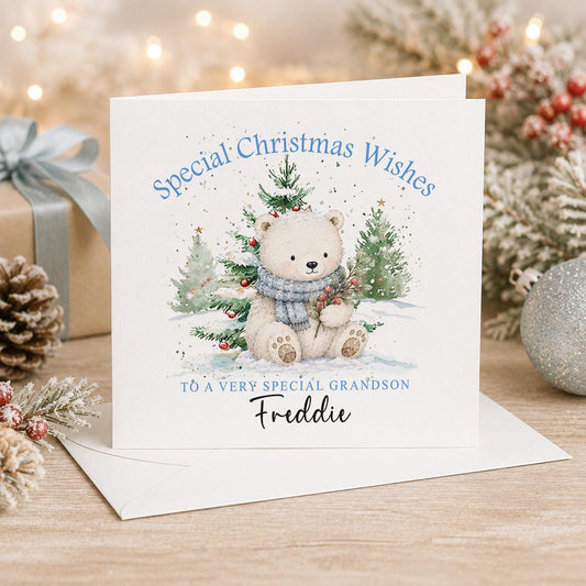 Personalised polar bear Christmas card, white 6x6 inch square card printed with a polar bear cub between snowy trees and a name