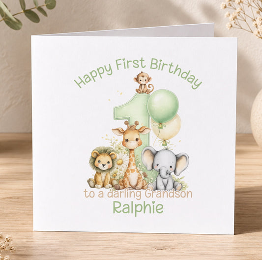 Personalised first birthday card featuring a cartoon lion, giraffe and elephant beside a green number 1, reading Happy First Birthday to a lovely Grandson Ralphie.