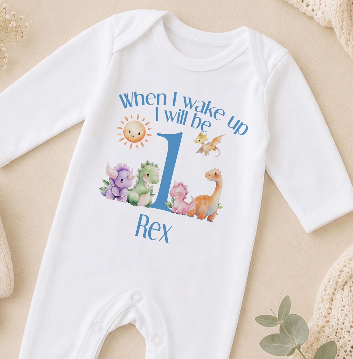 A white onesie with a personalized text and illustrations on it, specifically a dinosaur-themed design.