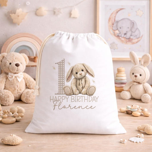 Personalised teddy and bunny birthday sack laid flat, showing the printed name and drawstring top