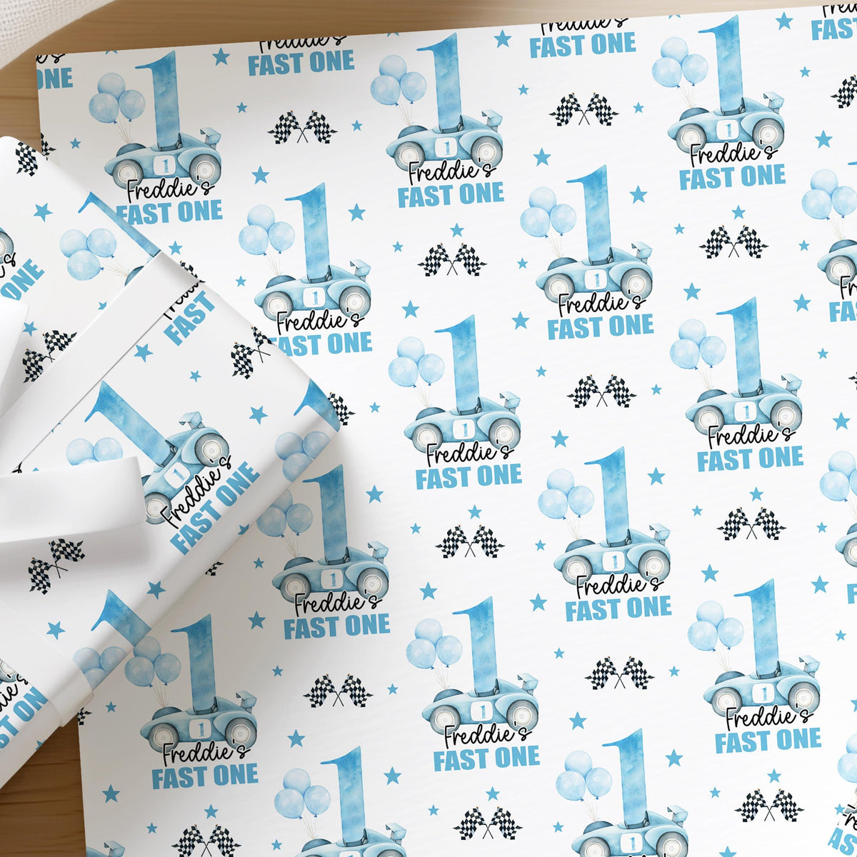 Personalised blue racing car birthday wrapping paper for boys with a custom name and racing flag design
