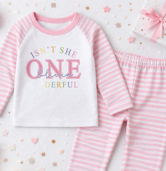 Personalised pink 1st birthday pyjama set printed with 'Isn't she ONE-derful' and the child's name