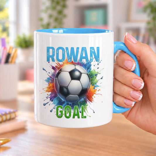 Personalised football mug with blue handle and inside, printed with a football bursting through a rainbow paint splash, a name in blue above and GOAL in green