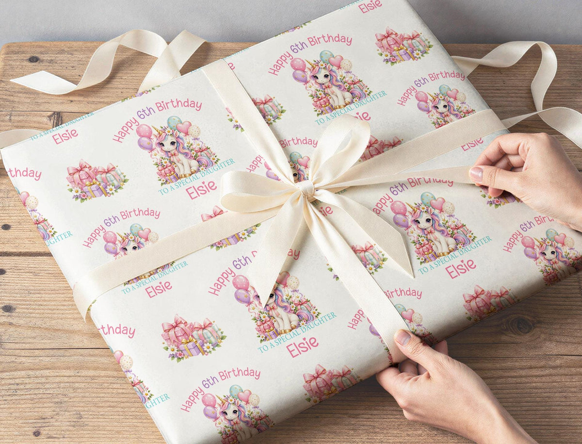 Gift box wrapped in personalised unicorn birthday wrapping paper with custom name and age, tied with cream ribbon
