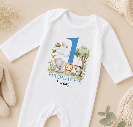 Personalised white baby vest printed with an elephant, lion and zebra safari scene, a blue number one and 'Birthday Boy Lucas'