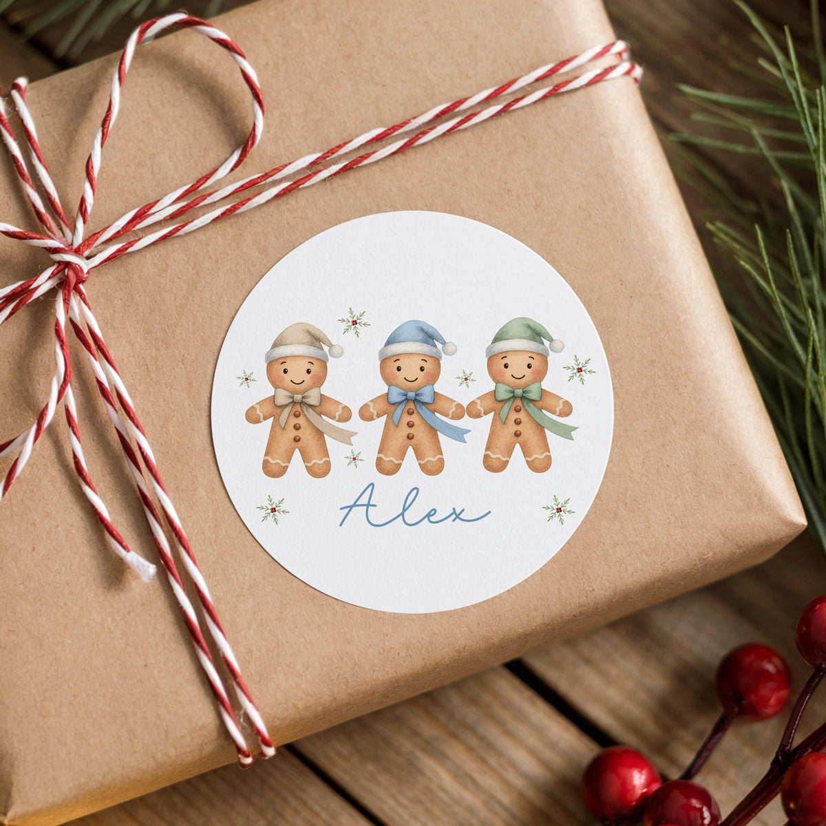 Personalised gingerbread trio Christmas sticker with custom name on a wrapped gift box with striped ribbon