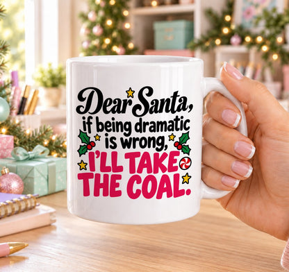 White 11oz ceramic Christmas mug printed with “Dear Santa, if being dramatic is wrong, I’ll take the coal.” in black and pink lettering with holly and peppermint sweets, held in a festive room