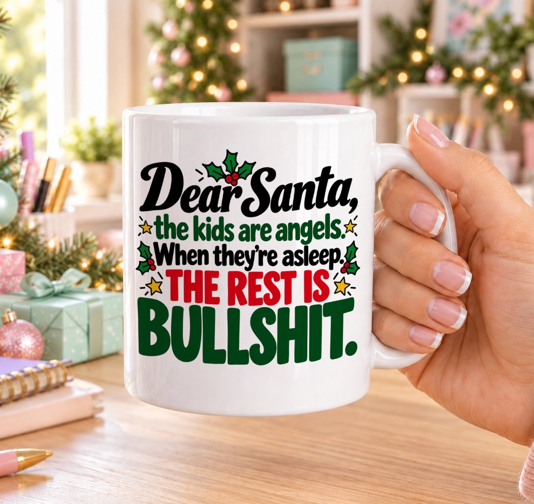 White 11oz ceramic Christmas mug printed with “Dear Santa, the kids are angels. When they’re asleep. The rest is bullshit.” in red, green and black lettering with holly and gold stars, held in a festive room