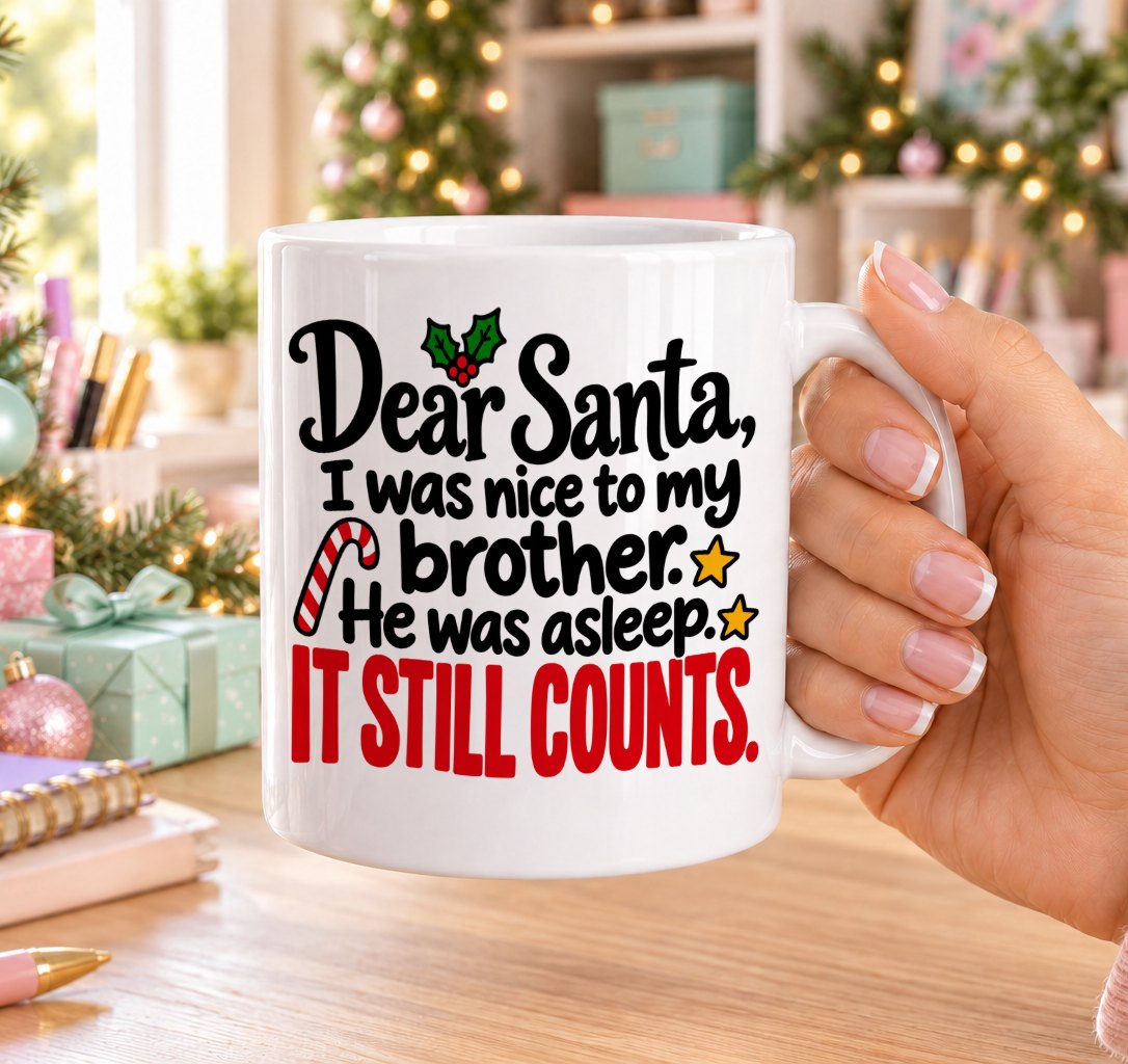 White 11oz ceramic Christmas mug printed with “Dear Santa, I was nice to my brother. He was asleep. It still counts.” in black and red lettering with holly, a candy cane and gold stars, held in a festive room