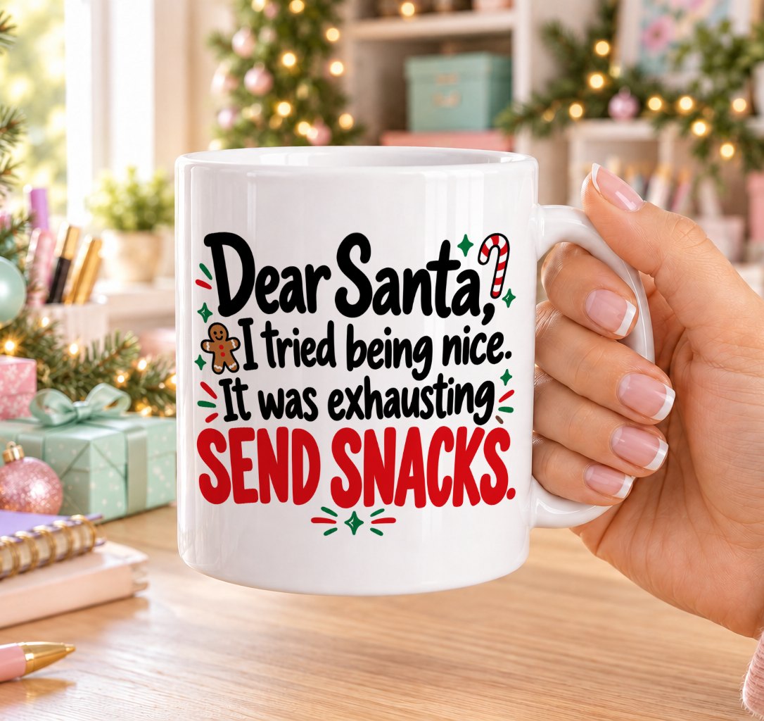 White 11oz ceramic Christmas mug printed with “Dear Santa, I tried being nice. It was exhausting. Send snacks.” in black and red lettering with a gingerbread man, candy cane and holly, held in a festive room