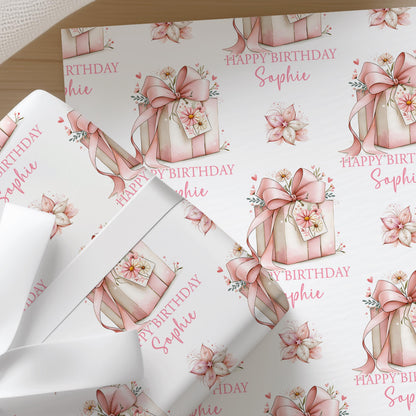 Personalised pink floral wrapping paper sheet laid flat showing the full repeating gift box and flower pattern with custom name and age.