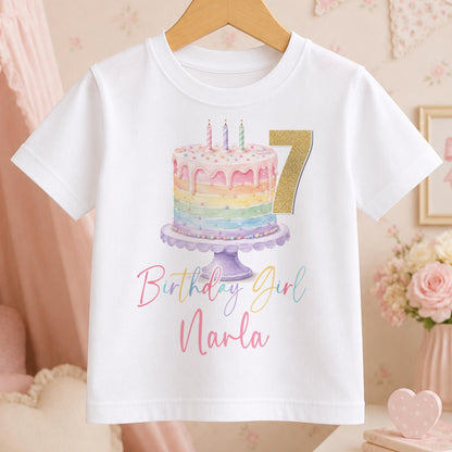 Personalised rainbow cake birthday t-shirt – white tee with a pastel rainbow cake with candles, gold number 7, and Birthday Girl Narla in pink script