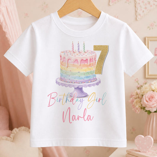 Personalised rainbow cake birthday t-shirt – white tee with a pastel rainbow cake with candles, gold number 7, and Birthday Girl Narla in pink script