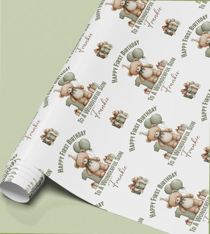 Sage green wrapping paper printed with a repeating pattern of teddy bears and balloons, with 'Happy First Birthday' and 'To a Wonderful Son' text.