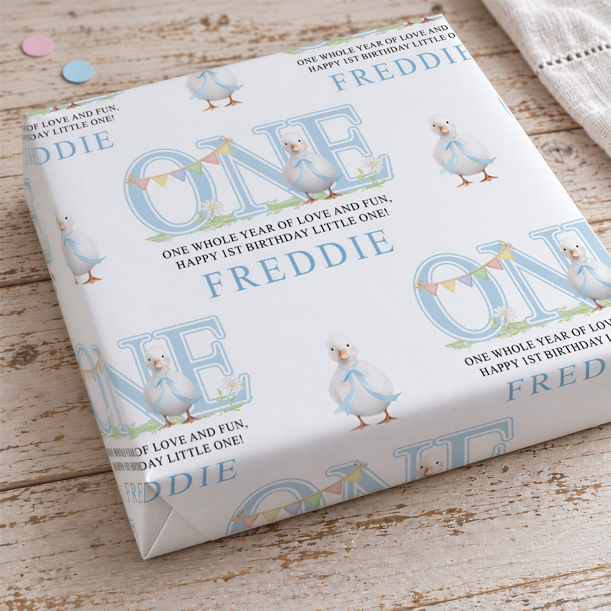 a white gift box with a repeating pattern of blue ducks and the name "FREDDIE" printed on it.
