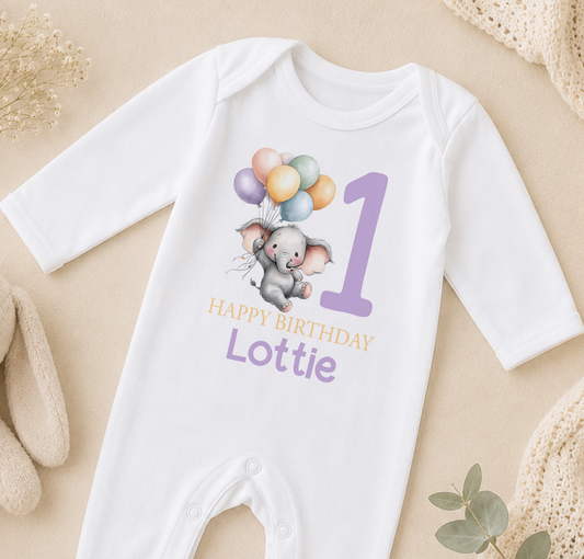 Personalised white baby vest printed with a floating cartoon elephant and balloons, and 'Happy Birthday Lottie' lettering