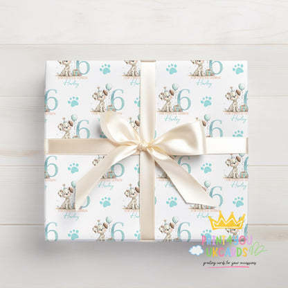 Personalised puppy wrapping paper laid flat, showing the full blue paw print pattern with custom name.