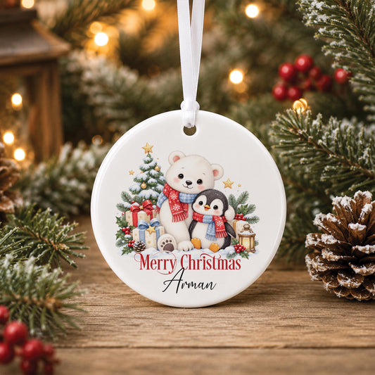 Personalised Christmas bauble, white ceramic ornament with a polar bear and penguin snowy design printed with a name, hanging on a Christmas tree