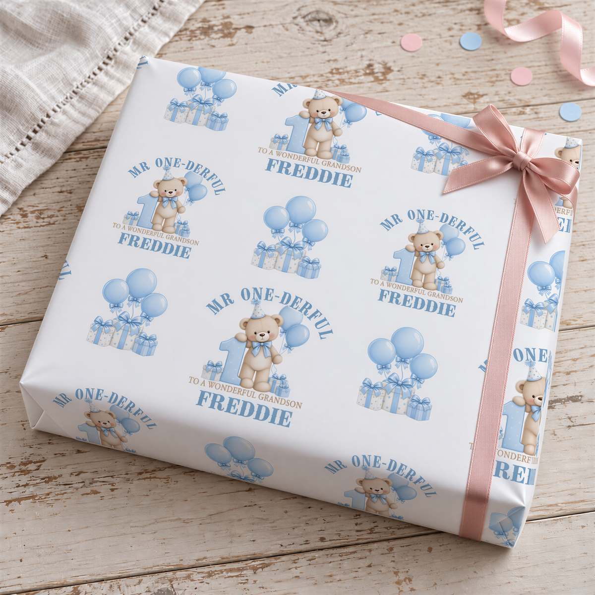 a gift box with a pattern of blue balloons and teddy bears, along with the text "MR ONE-DERFUL FREDDIE" printed on it.