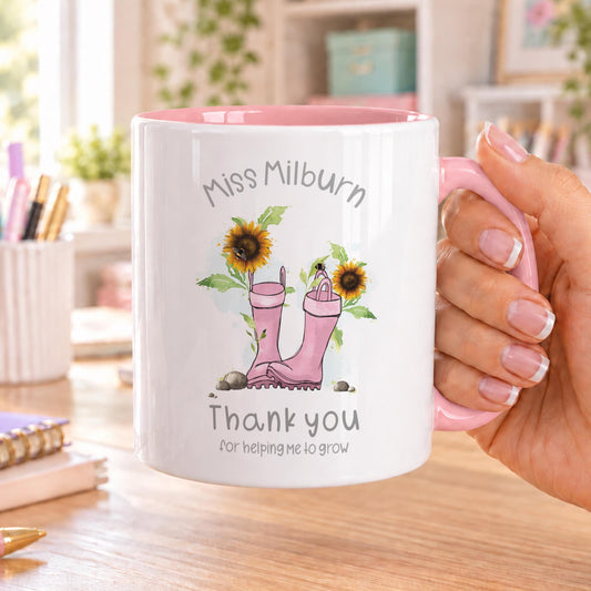 Personalised teacher mug with pink handle and inside, showing pink wellies with sunflowers, the teacher’s name above and Thank you for helping me to grow below