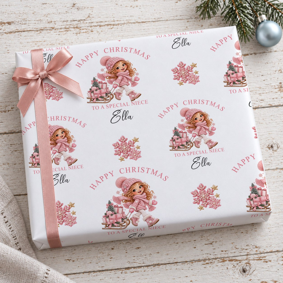 Gift wrapped in personalised girl and sledge Christmas wrapping paper tied with a pink satin bow