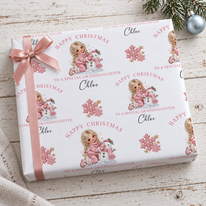 Gift wrapped in personalised girl and snowman Christmas wrapping paper tied with a pink satin bow