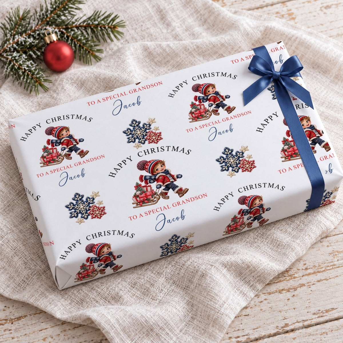 Gift wrapped in personalised grandson Christmas wrapping paper tied with a navy blue satin bow on a linen cloth