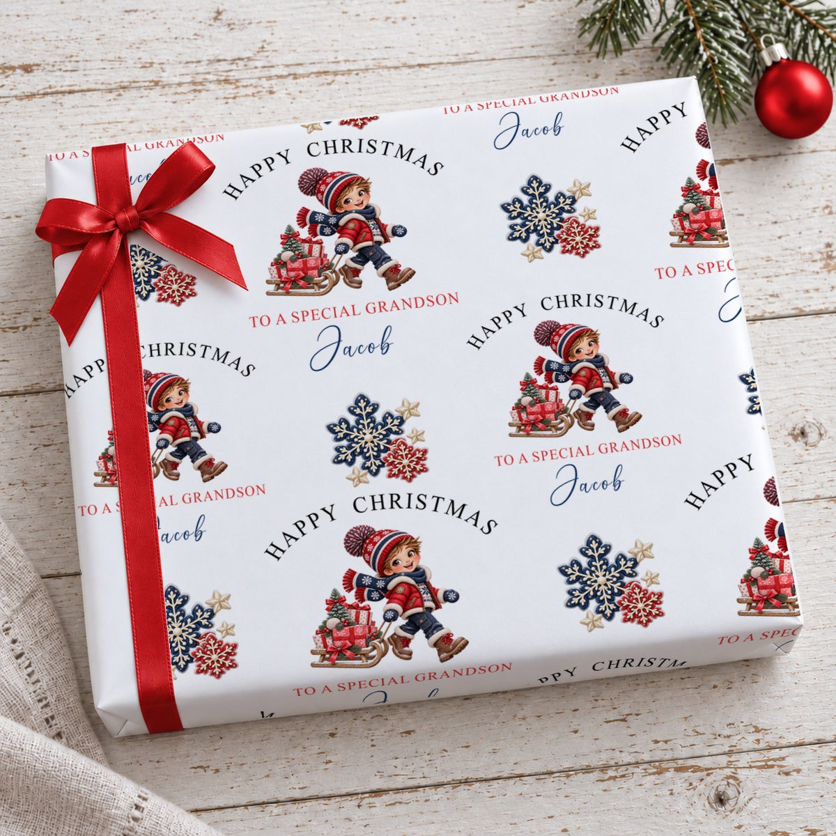 Present wrapped in personalised Happy Christmas To a Special Grandson Jacob paper with a red ribbon by a Christmas bauble