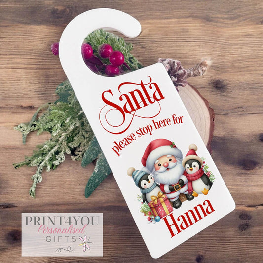 Personalised Santa Stop Here door hanger with Santa and two penguins design, custom name example printed on white acrylic Christmas Eve box sign