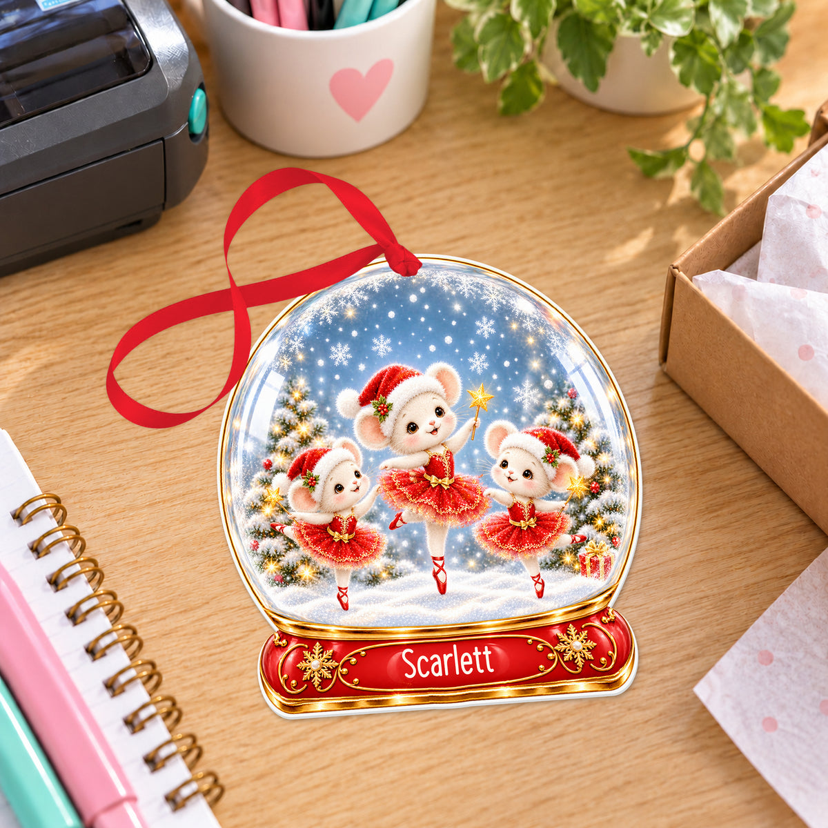 Personalised ballet mice snow globe bauble with name, white acrylic Christmas decoration with ribbon, shown on a desk
