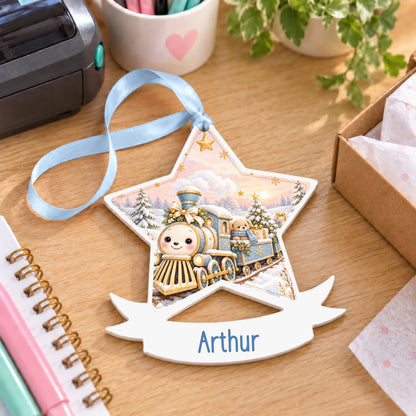 Personalised blue and gold Christmas train white acrylic star bauble with name, 10cm Christmas decoration with ribbon, shown on a desk