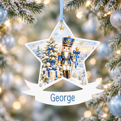 Personalised blue and gold nutcracker acrylic star Christmas bauble with custom name, hanging on a Christmas tree with baby blue ribbon