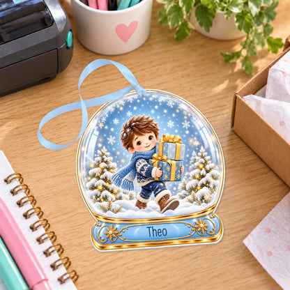 Personalised boy with blue gifts snow globe bauble with name, white acrylic Christmas decoration with ribbon, shown on a desk