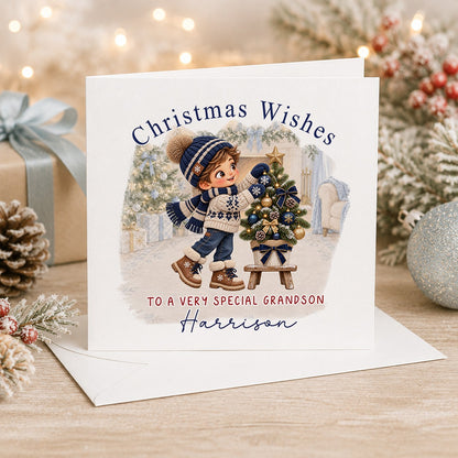 Personalised 6x6 Christmas Wishes card with a boy in a navy bobble hat and Nordic jumper decorating a little Christmas tree, “To a very special grandson Harrison”