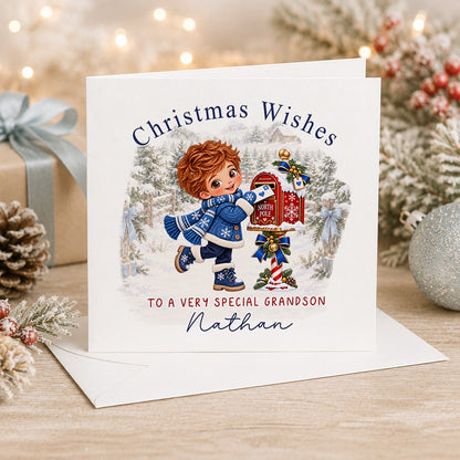 Personalised 6x6 Christmas Wishes card with a red-haired boy in a blue knitted coat posting a letter into a red North Pole postbox, “To a very special grandson Nathan”