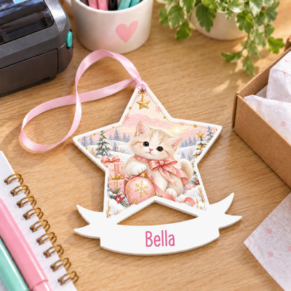 Personalised Christmas kitten white acrylic star bauble with name, 10cm Christmas decoration with ribbon, shown on a desk