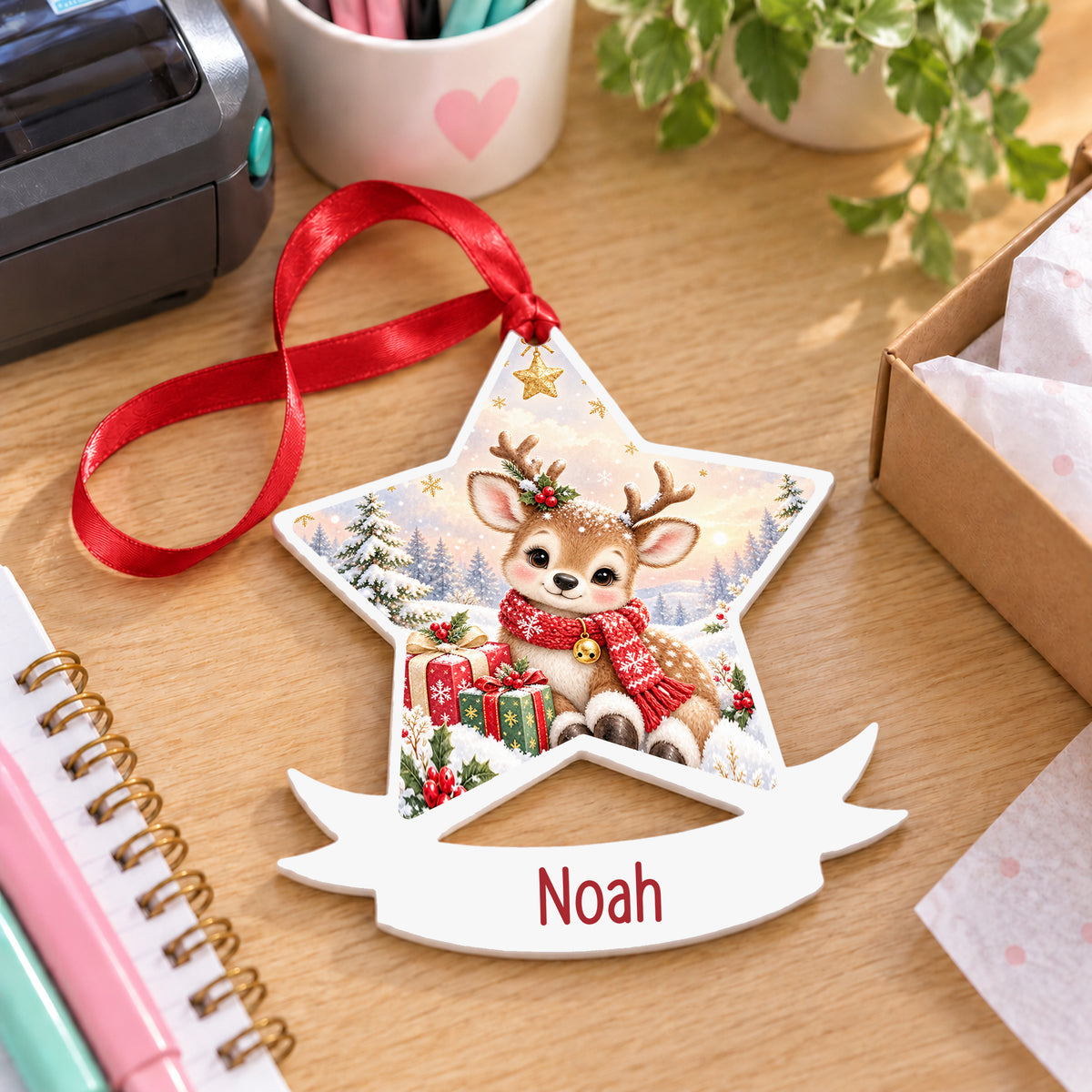 Personalised classic Christmas reindeer white acrylic star bauble with name, 10cm Christmas decoration with ribbon, shown on a desk