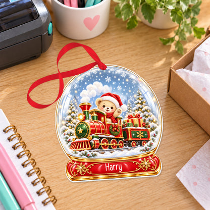 Personalised classic Christmas train snow globe bauble with name, white acrylic Christmas decoration with ribbon, shown on a desk