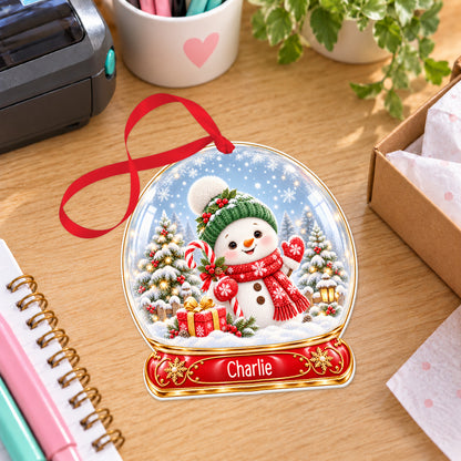 Personalised classic snowman snow globe bauble with name, white acrylic Christmas decoration with ribbon, shown on a desk