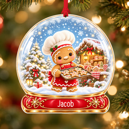 Personalised gingerbread baker acrylic snow globe Christmas bauble with custom name, hanging on a Christmas tree with red ribbon